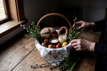 Traditional Easter basket with painted egg sausage bread salt and boxwood decoration on white lace napkin for holiday blessing ceremony and family breakfast celebration