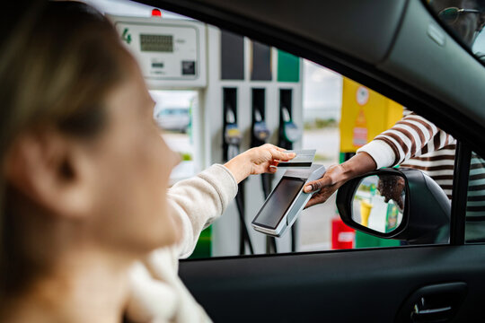 Woman making credit card payment at gas station pump
