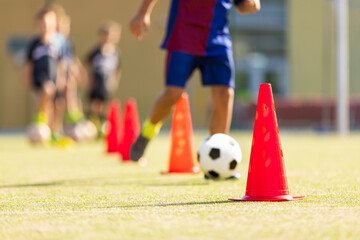 Obraz premium Kids Soccer Dribbling Drill with Cones; Youth Football Training Focused on Ball Control