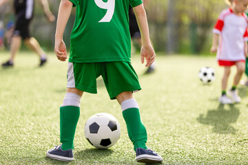 Child Soccer Player in Green Jersey Controlling Ball  Youth Football Training on Grass Field © matimix