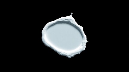 A blob of white cosmetic cream on a black background viewed from directly above