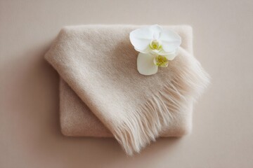 luxurious home decor, neat, luxurious flat lay featuring a folded cashmere throw, matte travertine coaster, a white orchid stem, on a light beige background with soft, diffused light