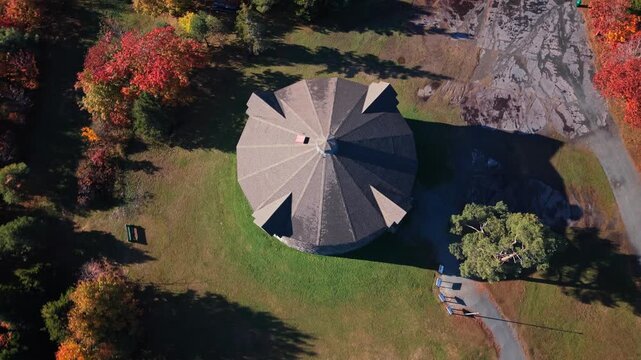 Drone Flies Over Prince Of Wales Tower National Historic Site, Bathed In Morning Light. Fall Foliage Surrounds This Landmark In Canadian Coastal Parkland.