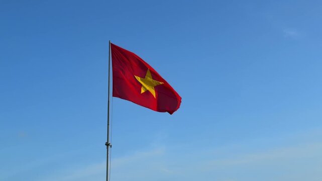 Slow motion Vietnam flag gently flowing in steady wind, clearly showing national colors against open sky with soft evening sunlight in the background. Patriotic symbol.
