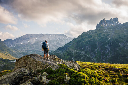 Man hiker looking at mountain peak in Styria, Austria. Epic alpine landscape with backpacker hiking during sunset in Alps mountains