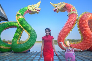 Young girl in traditional dress with colorful serpent statues