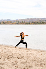 Obraz premium Fit woman doing yoga exercise by river in autumn season.