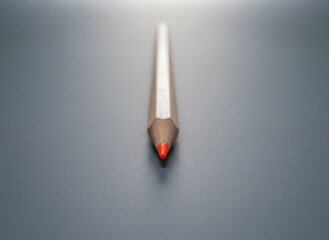 A sharp red pencil tip against a grey background, emphasizing focus, precision, and standing out in education or creative concepts