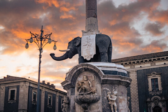 The Elephant Fountain, symbol of Catania, stands in Piazza Duomo at sunset under dramatic sky