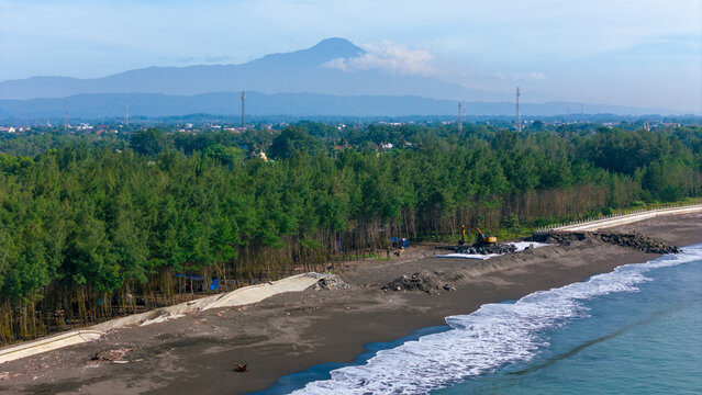 Mountains loom over cilacap seaside town with lush trees ideal for nature, travel, coastal, landscape, and vacation related designs.