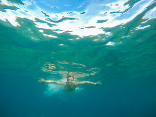 Obraz premium Young woman posing while swimming underwater with snorkel mask on a summer day