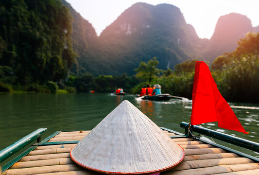 Exploring scenic waterways in Ninh Binh, Vietnam with traditional conical hat on boat