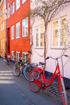 Quiet street sidewalk holds bicycle in red against colorful facade architecture in copenhagen denmark as spring daylight settles softly
