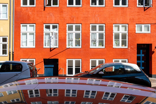 Street reflection shows car and red facade windows with architecture details in copenhagen denmark as spring day stays bright today