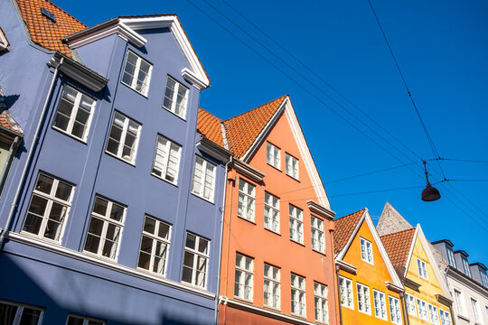 City gables and sky with lamp wires over colorful houses reveal architecture character in copenhagen denmark as spring days clear again