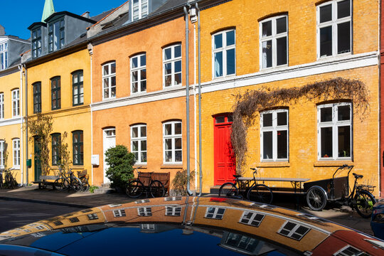 Street scene with bicycle near colorful facade door and reflection showing architecture in copenhagen denmark as spring sunlight hits