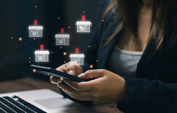 Businesswoman using smartphone with multiple store icons and location pins, representing omnichannel retail, store location strategy, digital commerce expansion, and customer reach management.