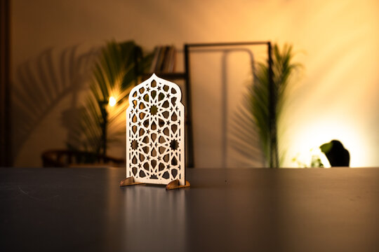 Islamic wooden ornament with geometric pattern on desk, ramadan kareem and eid mubarak decoration with warm interior lighting and copy space
