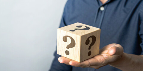 Business concept with decision making and problem solving along with a person holding a wooden cube toy with a question mark.