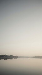 Fototapeta premium Serene lake at dawn with lone boat and misty atmosphere creating peaceful morning landscape for meditation and wellness content.