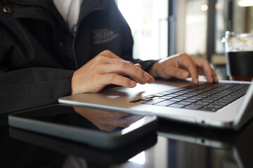 Close-up of hands typing on a laptop keyboard, remote work or digital nomad lifestyle.