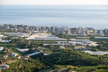 Obraz premium Expansive View of Coastal Town With Greenhouses and Urban Development During Sunset