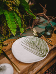 Boho table with plates, gold cutlery and candles on rustic wooden pallets