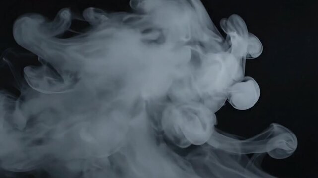 Smoke rises as it expands in a dark space during a creative art project in a home studio