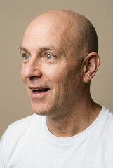 Obraz premium Bald middle aged man with green eyes wearing a white t-shirt in a studio portrait.