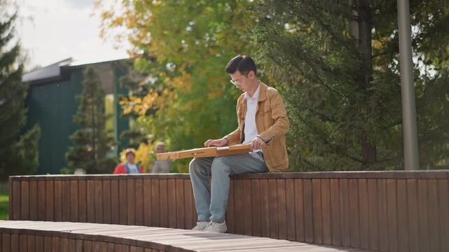 artist painting on park bench, refining ink and watercolor lines with portable wooden box palette, capturing campus architecture and autumn foliage, closing sketchbook and packing up, standing ready
