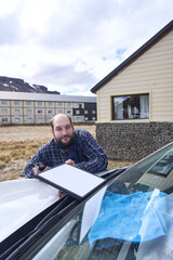 Man positioning a satellite internet receiver antenna on the front of his car to get a signal and connect to the network while traveling. Technology allows to stay connected from remote locations.