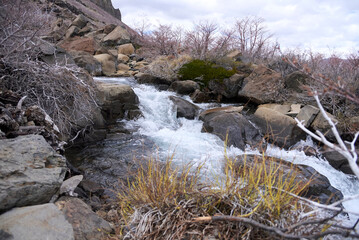 Winter landscape in Caviahue, Neuquen, Argentina: Arroyo de la Usina stream surrounded by rocks and leafless vegetation.