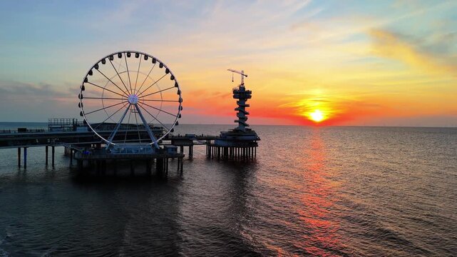 Sunset on the beach in The Hague, Netherlands. The North Sea coast, Scheveningen Pier and the famous Ferris wheel SkyView de Pier.	