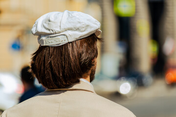 Single person stands with their back to the camera, creating an anonymous lifestyle scene focused on contemplation and everyday movement in the city. The shallow depth of field emphasizes solitude and