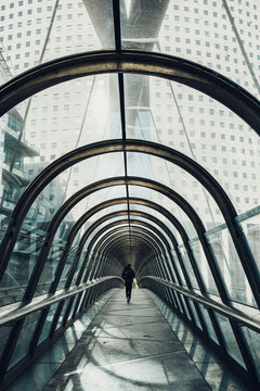 Corporate modern urban architecture forms glass tunnel corridor walkway in Paris La Defense with symmetry and cool daylight creating futuristic passage
