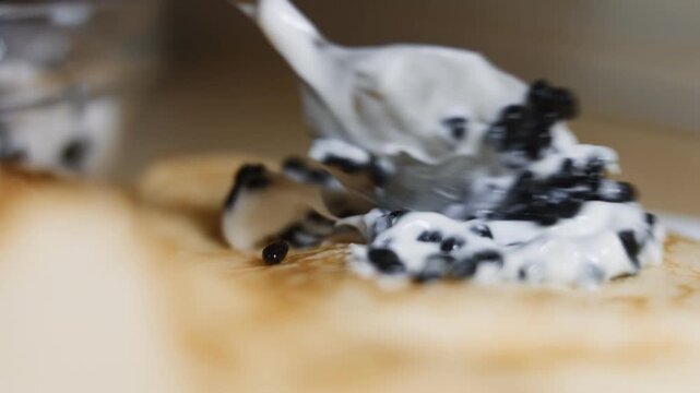 Spreading lump fish black roe with taramasalata on blinis, macro