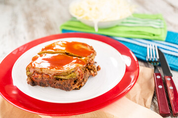 A serving of courgette and eggplant moussaka topped with a thick red tomato sauce.
