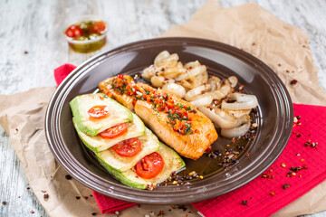 A dish of salmon with zucchini and onions served on a plate.