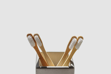 Eco-friendly wood toothbrushes with soft white bristles in modern grey concrete holder at sunlight. Minimal design, sustainable hygiene concept, Zero waste lifestyle, eco-conscious living, hard shadow
