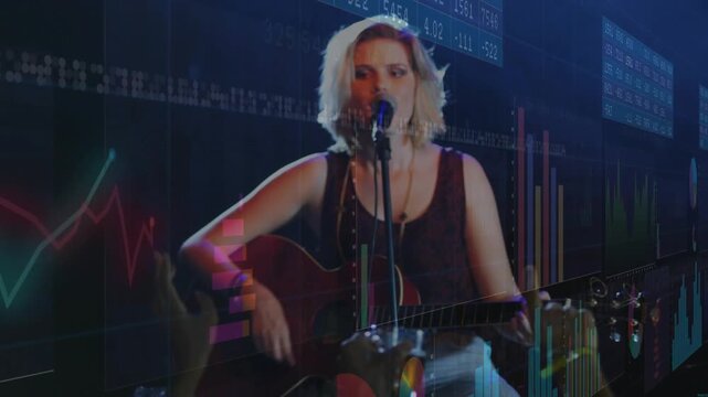 Female singer singing playing guitar, camera zooming causing charts settling behind her for crowd
