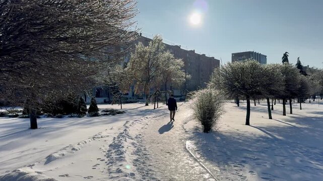 A guy walks through the snow on a frosty, beautiful day.