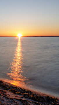 Sonnenuntergang am Strand von Timmendorfer Strand - Ruhiger Sonnenuntergang am Timmendorfer Strand mit warmen Farben, glattem Wasser und minimalistischem Lichtweg im Hochformat.