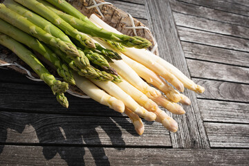 White and green asparagus in a basket on gray wood. Background for a healthy nutrion concept. Top view.