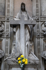 Old statue with cross in cemetery. Dramatic mysterious figure, no people.