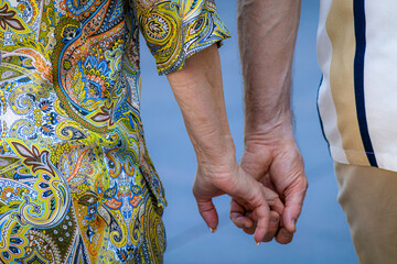 Close-up of two seniors hands clasped gently captures intimacy and emotional connection in everyday life. The scene conveys trust, care, and the comfort of long-term partnership.