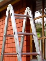 A metal ladder with rain drops standing next to a house