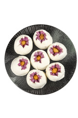Assorted fancy Asian dessert buns with hibiscus flowers and runny egg yolk centers on dark plate