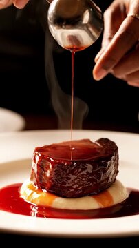 chef pours rich sauce over tender filet mignon on mashed potatoes in a fine dining setting