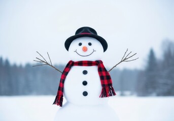 Fototapeta premium A cheerful snowman wearing a black hat and a red and black checkered scarf stands in a snowy landscape with trees in the background