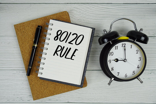 80 20 Rule text written on notepad with alarm clock on wooden background